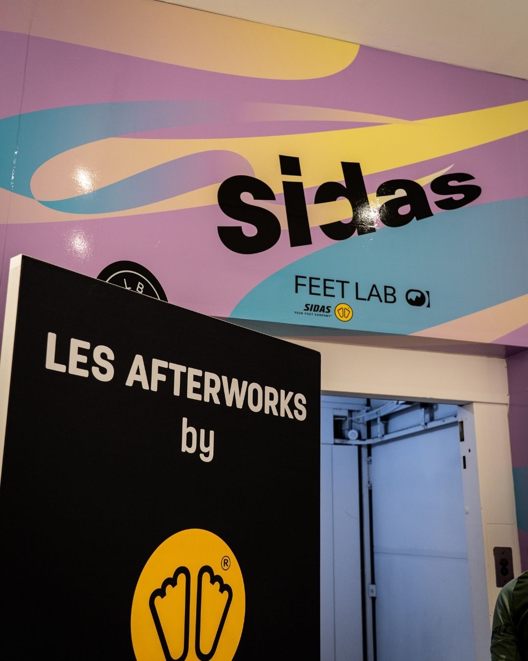 poster avec le logo sidas sur un fond coloré type peinture à l'eau violet, bleu et jaune.